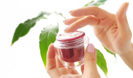 Female hands with a cosmetic cream on the white background