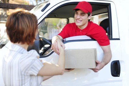 happy postal delivery courier in a van delivering package and handshake